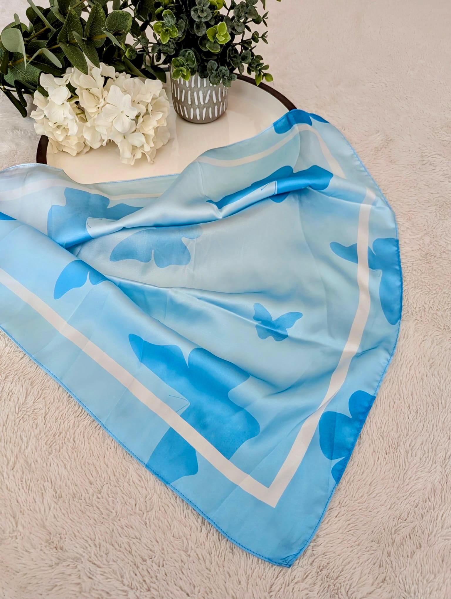 Blue butterfly patterned scarf on a textured surface with decorative elements.