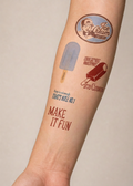 A close-up of a person's forearm featuring temporary tattoos with ice cream and popsicle designs, including a circular 'Ice Cream Stand' logo, a blue popsicle, a red ice cream cone, and the text 'MAKE IT FUN'.