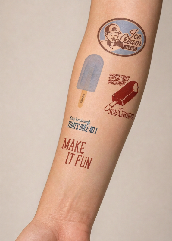A close-up of a person's forearm featuring temporary tattoos with ice cream and popsicle designs, including a circular 'Ice Cream Stand' logo, a blue popsicle, a red ice cream cone, and the text 'MAKE IT FUN'.